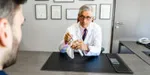 Dr Gazielly examines an anatomical shoulder model with a patient